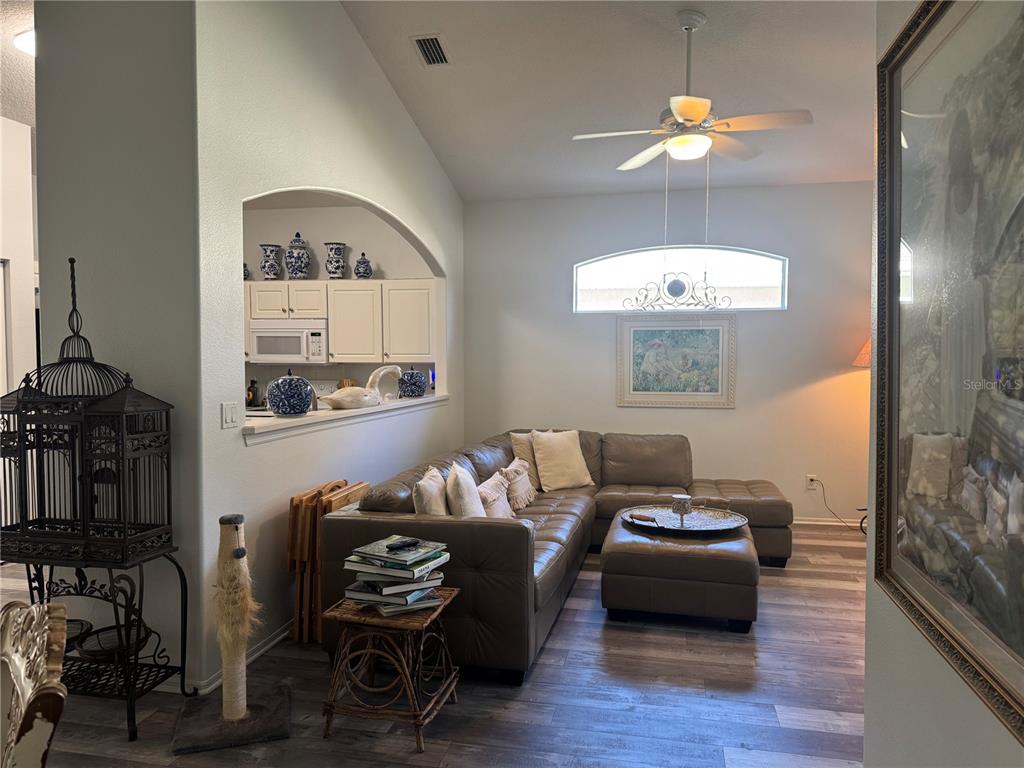 A living room features a leather sectional, a ceiling fan, and an arched kitchen pass-through — 16 SUMMER TERRACE UNIT 16, PALM COAST, FL