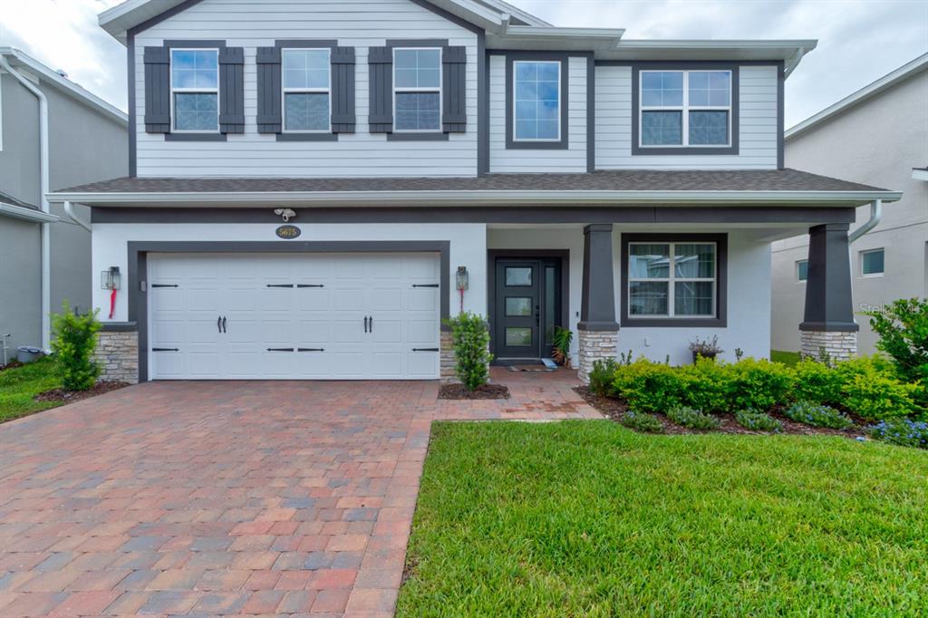 A two-story house features a white garage, a front door, and a brick driveway — 5675 GREEN ARROW PLACE, SANFORD, FL