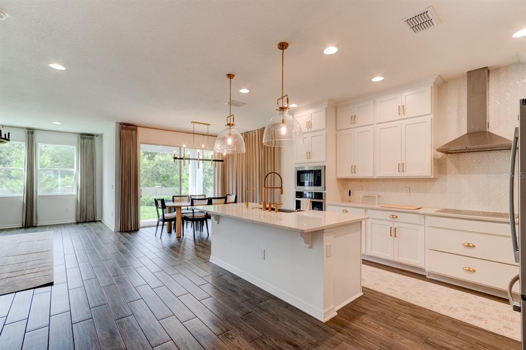 A modern kitchen with white cabinets, a central island, and wood-look tile flooring — 5675 GREEN ARROW PLACE, SANFORD, FL