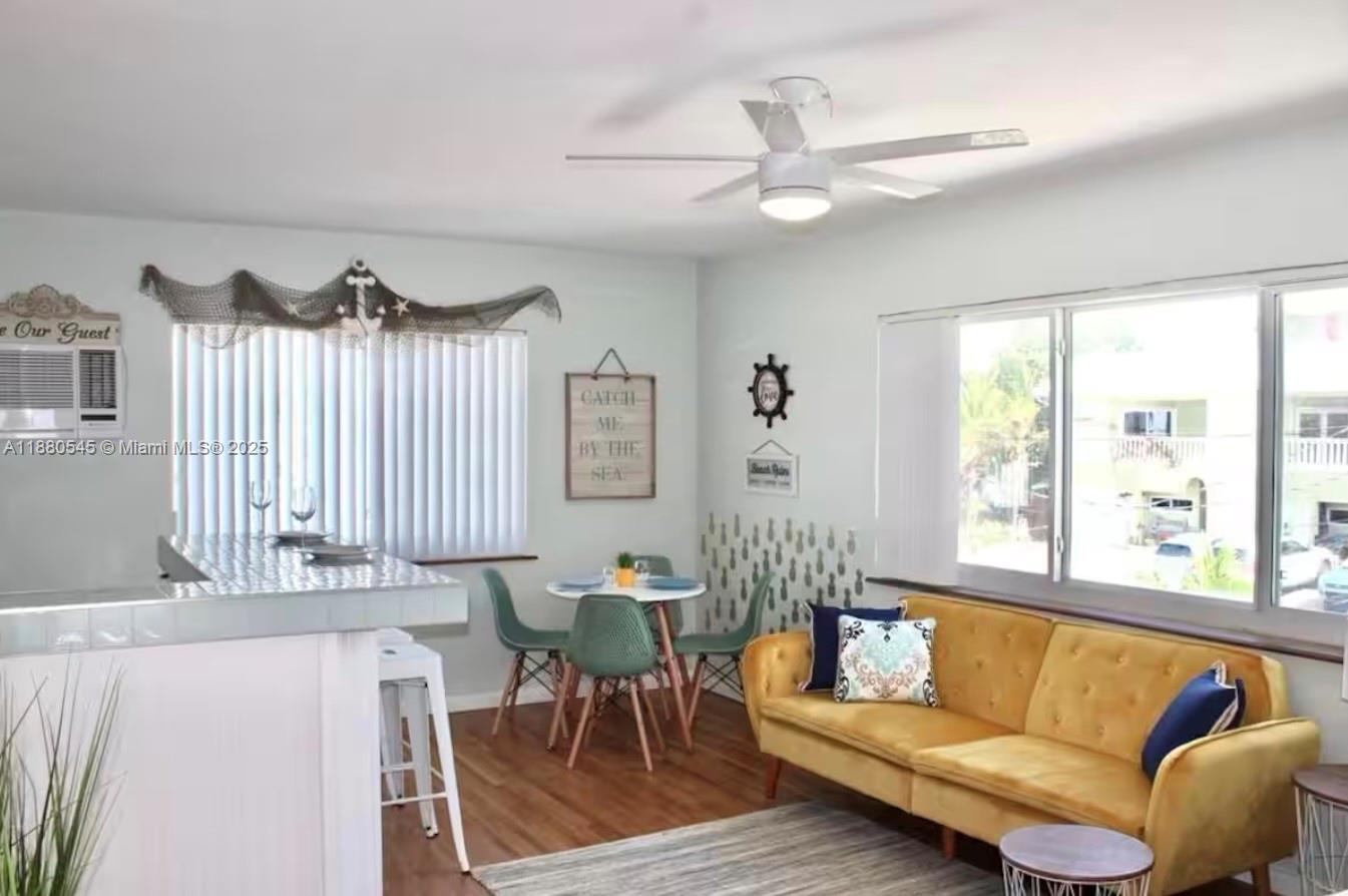 A living and dining area features a yellow sofa, a small round table, and coastal decor — 316 Walnut St # 2, Hollywood FL 33019, HOLLYWOOD, FL