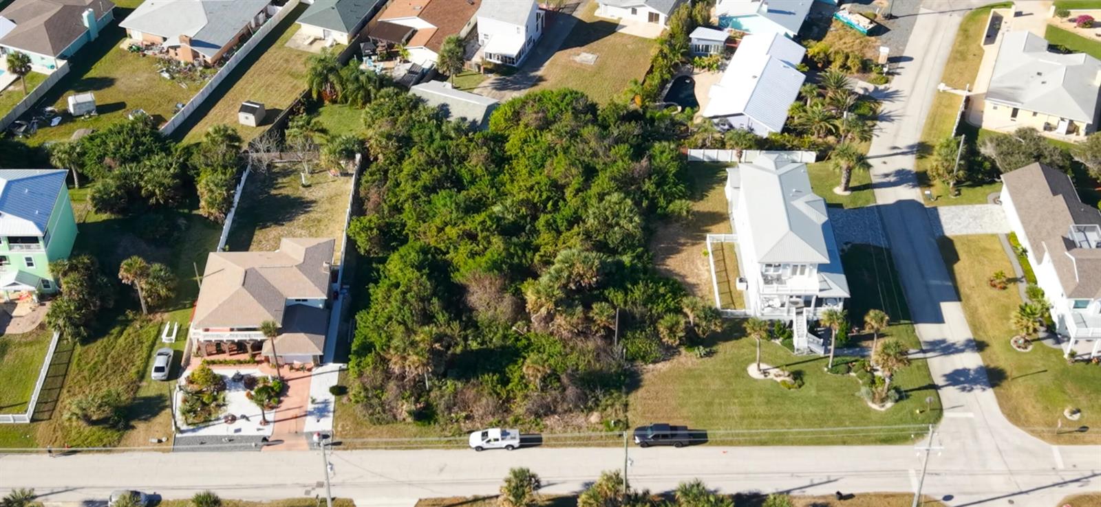 An aerial view shows a vacant, wooded lot situated between two residential houses — 1945 N Central Avenue, FL 32136, FL