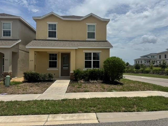 A two-story tan house with a front porch and a paved walkway — 269 BELLA PRESTWICK BOULEVARD, DAVENPORT, FL