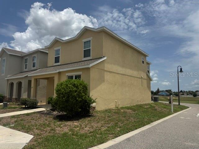 A two-story yellow stucco house with a covered entryway and a side yard — 269 BELLA PRESTWICK BOULEVARD, DAVENPORT, FL