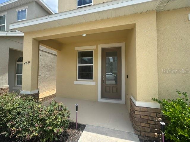 A covered front porch leads to a brown front door with a glass insert — 269 BELLA PRESTWICK BOULEVARD, DAVENPORT, FL