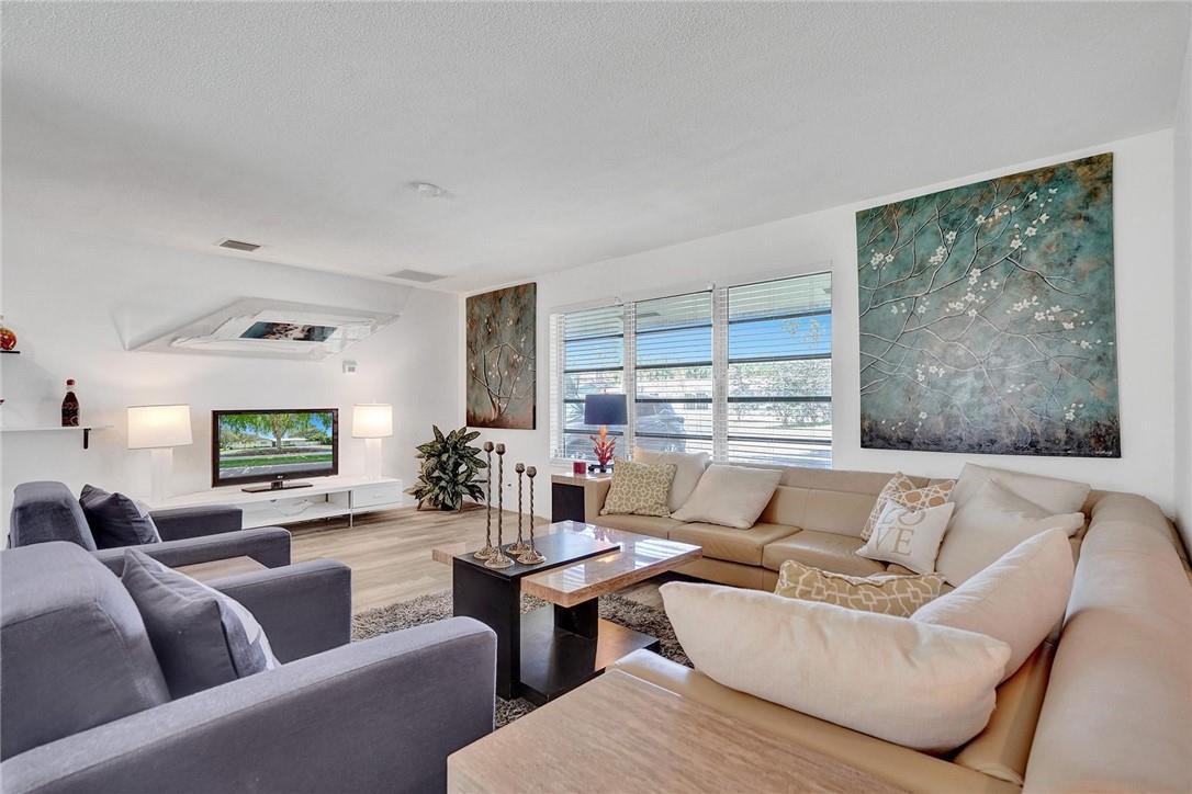 A living room features a beige sectional sofa, gray armchairs, a television, and wall art — 5101 NE 27th Avenue, Lighthouse Point FL 33064, LIGHTHOUSE POINT, FL