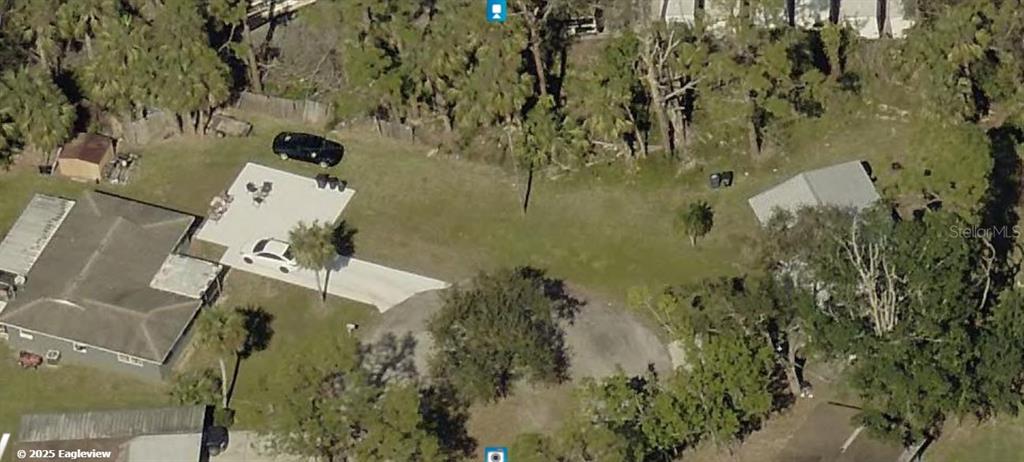 An aerial view shows two houses on a grassy lot with a concrete driveway and trees — 1826 BEACHWOOD DRIVE, NORTH FORT MYERS, FL