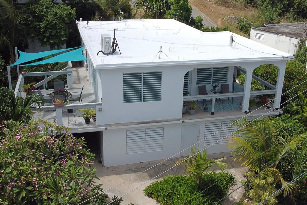 An elevated two-story white house with a flat roof, wrap-around balcony, and turquoise shade sail — 645 CASA RINCON, VIEQUES, PR