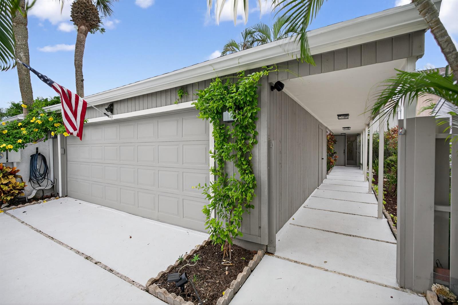 A gray garage with a climbing vine and a covered walkway leading to the entrance — 17145 Bay Street, Jupiter FL 33477, JUPITER, FL