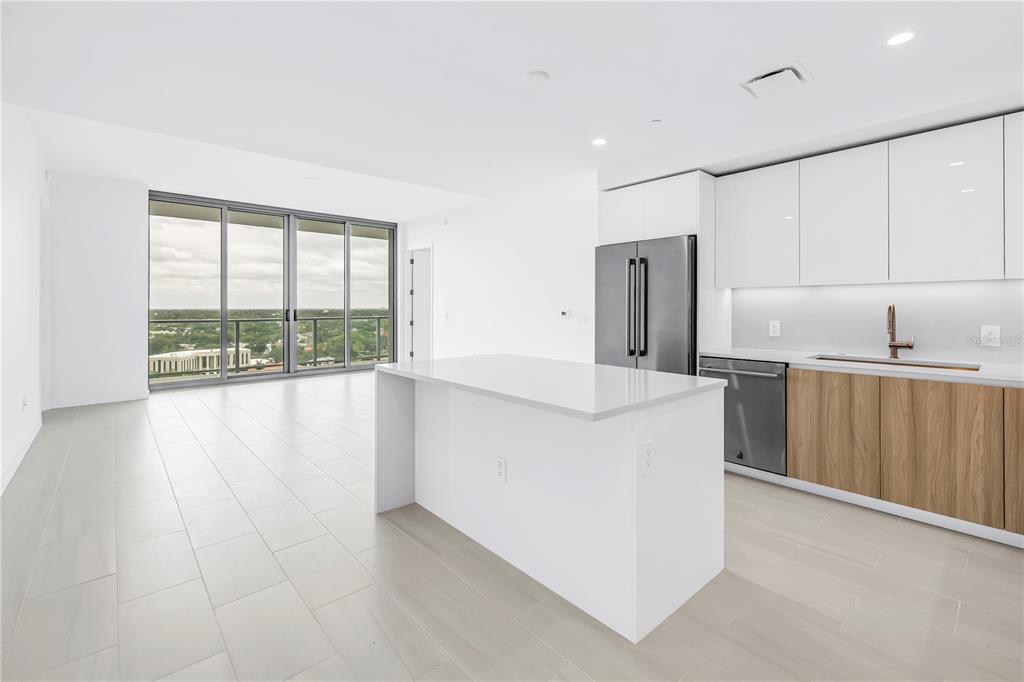 A modern kitchen with white cabinets, wood-tone lower cabinets, and an island overlooks a balcony — 400 CENTRAL AVENUE UNIT 1608, ST PETERSBURG, FL