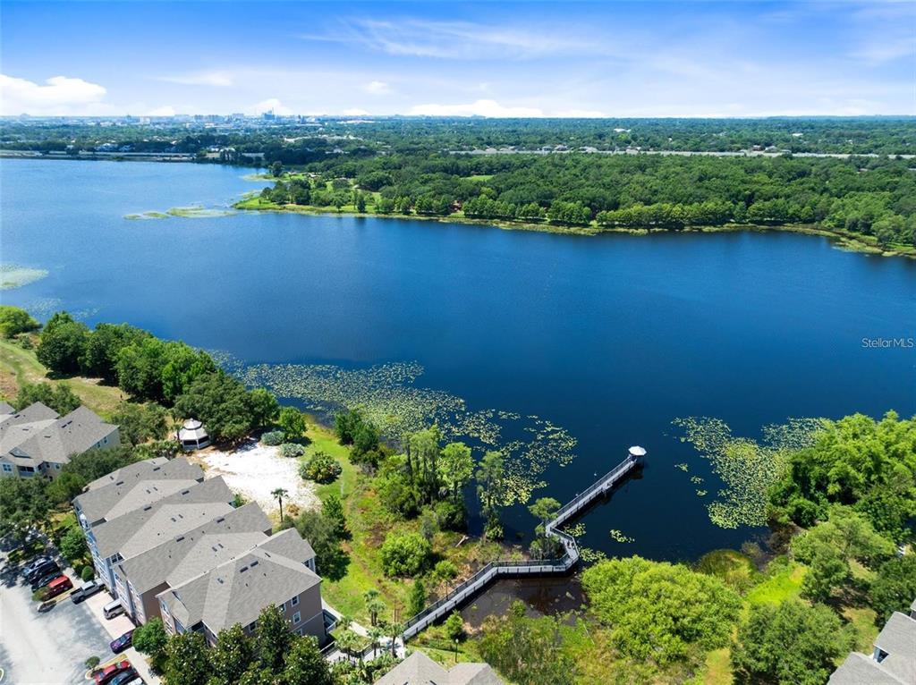 An aerial view shows a lake with a wooden pier and surrounding apartment buildings — 3446 SOHO STREET UNIT 108, ORLANDO, FL