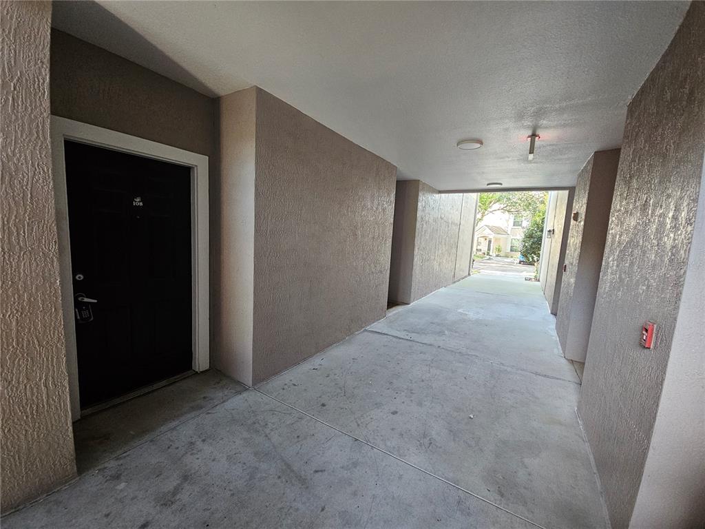 A concrete walkway leads to a black door labeled 108 under a covered building breezeway — 3446 SOHO STREET UNIT 108, ORLANDO, FL