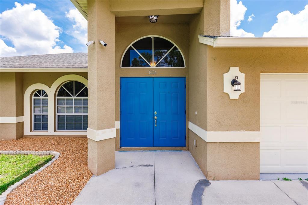 The exterior of a house features a blue double front door and an arched window — 3036 ABBINGTON STREET, NORTH PORT, FL