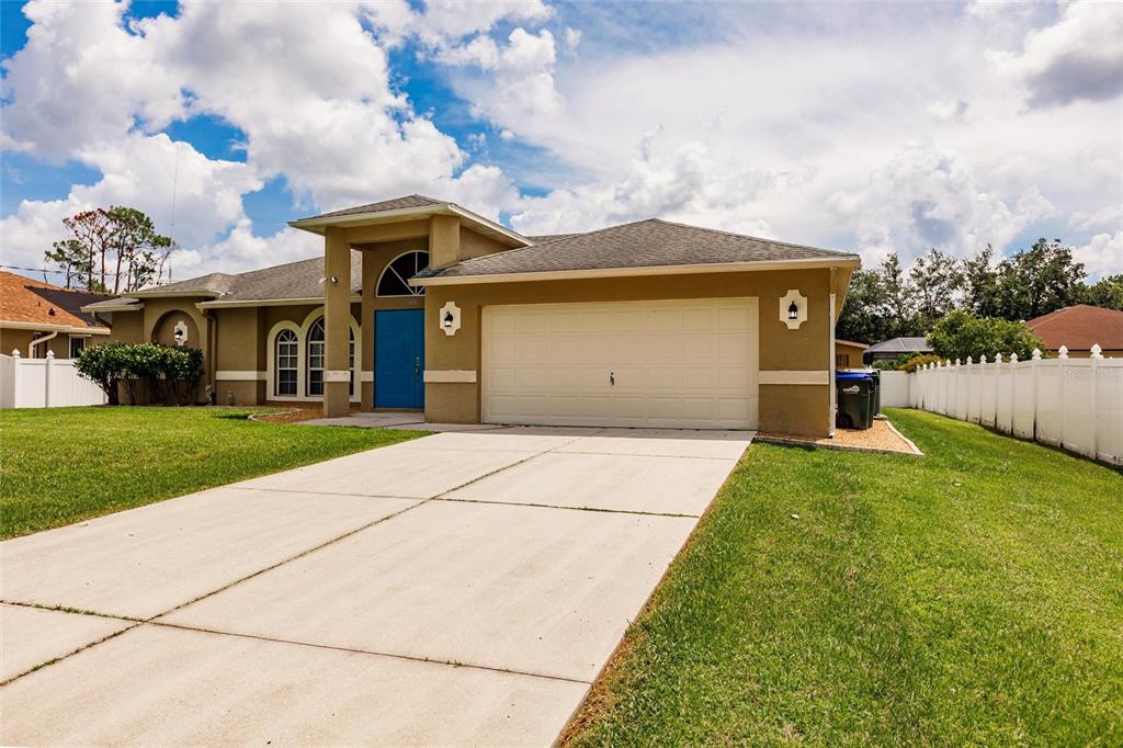 A tan single-story house with a blue front door, two-car garage, and a concrete driveway — 3036 ABBINGTON STREET, NORTH PORT, FL