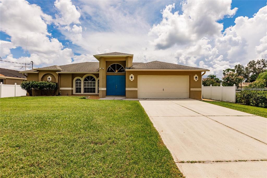 A tan single-story house features a bright blue double front door and a concrete driveway — 3036 ABBINGTON STREET, NORTH PORT, FL