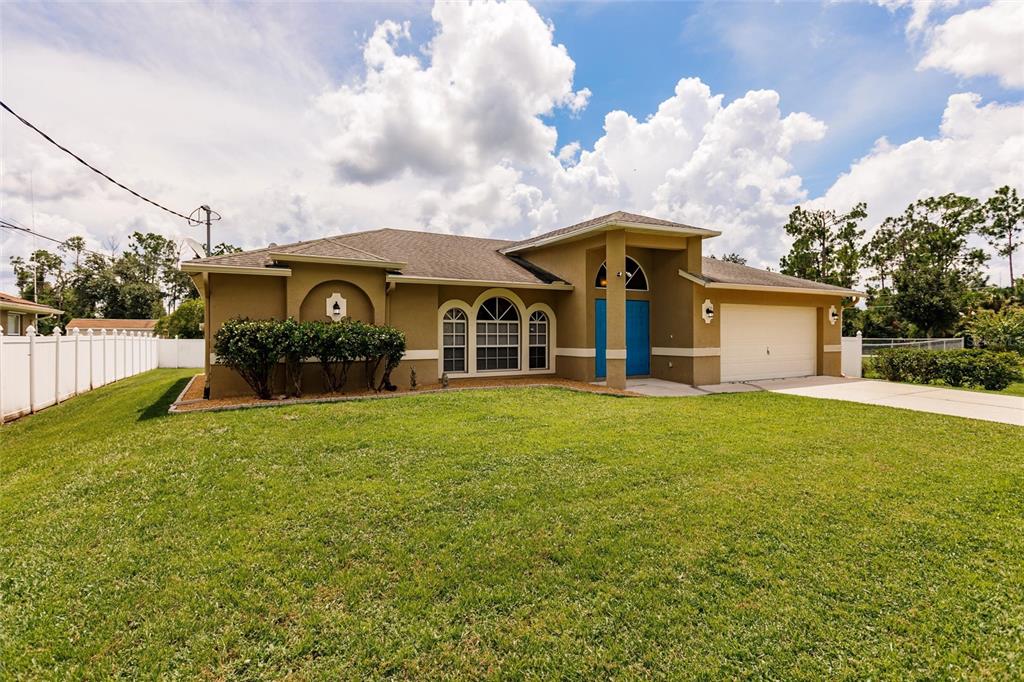 A tan single-story house with a two-car garage and a large front lawn — 3036 ABBINGTON STREET, NORTH PORT, FL