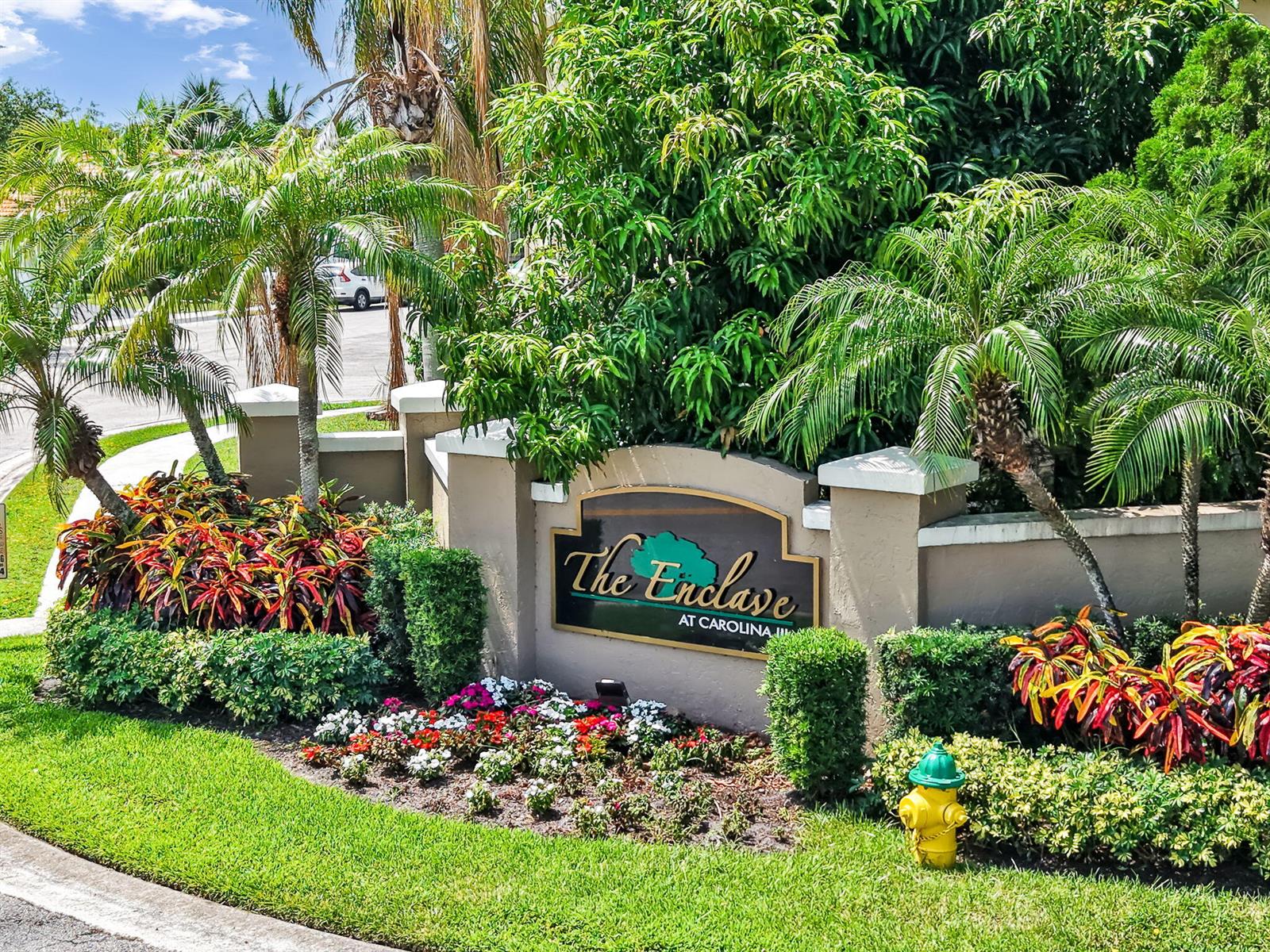 A sign for The Enclave at Carolina sits in a landscaped garden with palm trees — 3364 NW 79th Avenue, Margate FL 33063, MARGATE, FL