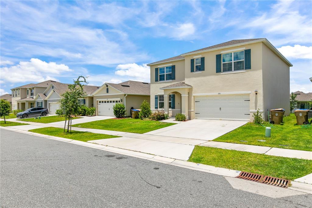 A two-story suburban house with a beige stucco exterior and a two-car garage — 1591 BARBERRY DRIVE, KISSIMMEE, FL