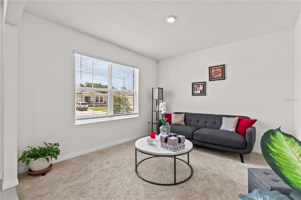 A living room features a grey sofa, a round marble coffee table, and a large window — 1591 BARBERRY DRIVE, KISSIMMEE, FL