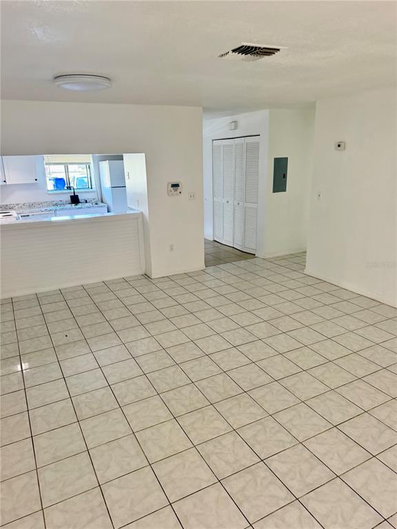 An open-concept living area features white tiled floors, a kitchen pass-through, and louvered closet doors — 1549 TANGELO CIRCLE, KISSIMMEE, FL