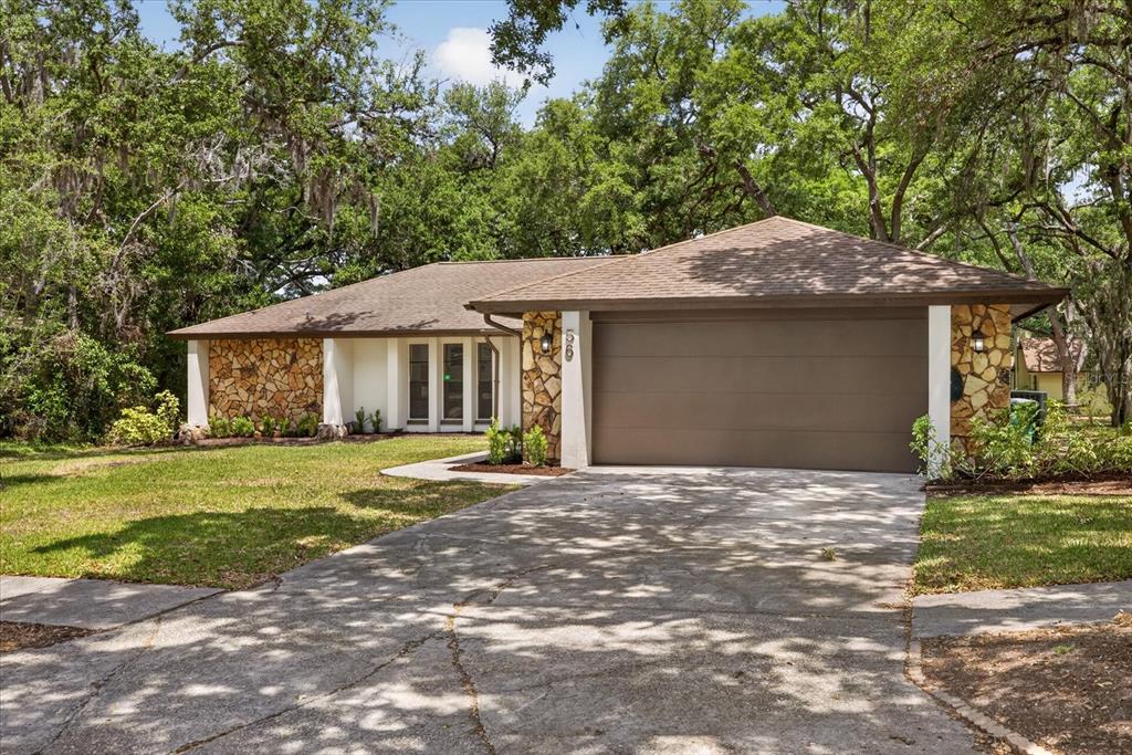 A single-story house with a stone facade, a two-car garage, and a concrete driveway — 56 BAY WOODS DRIVE, SAFETY HARBOR, FL