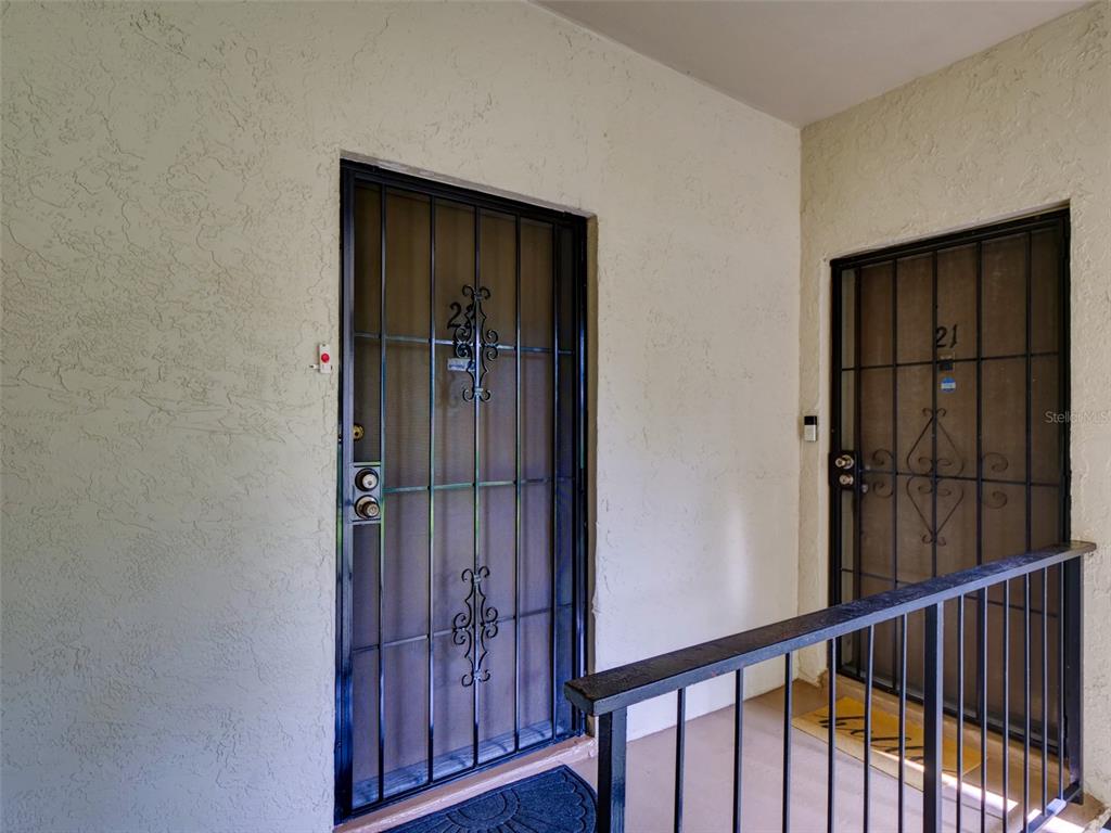 Two apartment entry doors with black security screens are located on a covered outdoor walkway — 3242 S SEMORAN BOULEVARD UNIT 22, ORLANDO, FL
