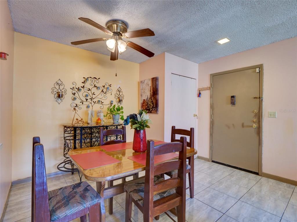 A dining room features a wooden table, chairs, a ceiling fan, and tile flooring — 3242 S SEMORAN BOULEVARD UNIT 22, ORLANDO, FL