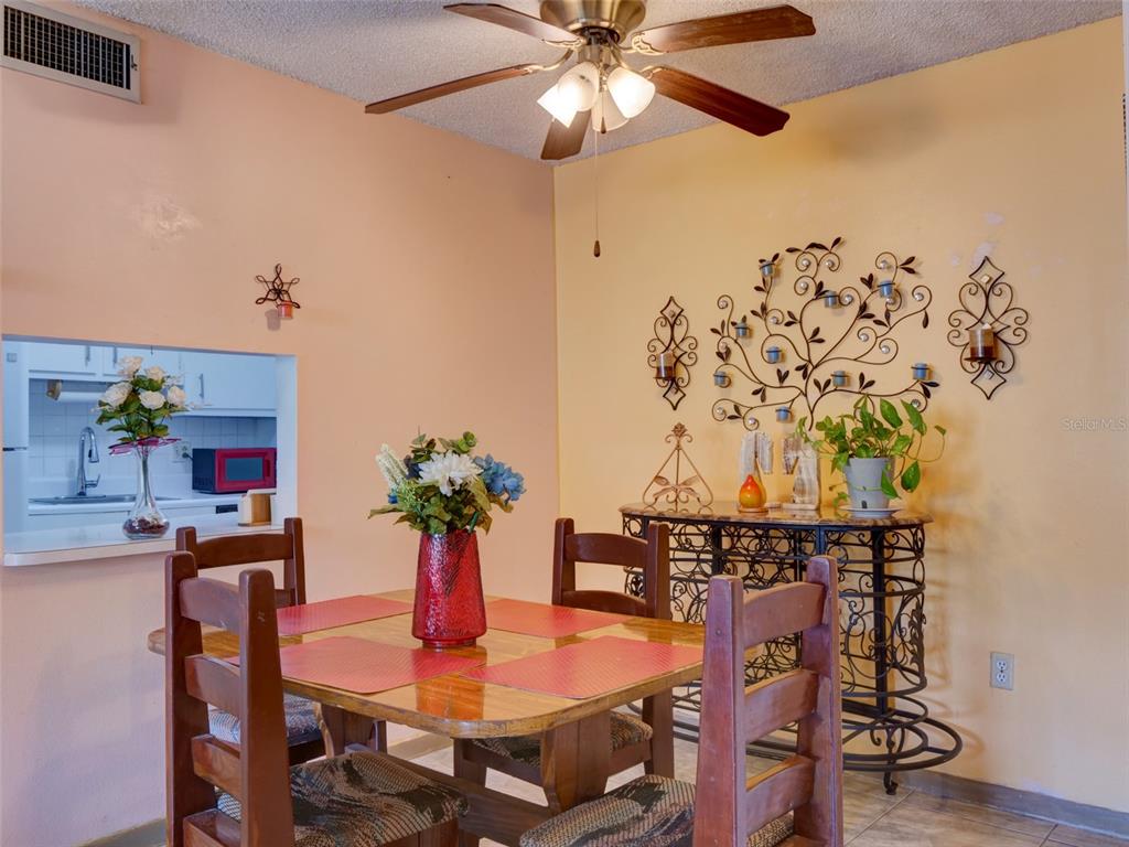 A dining room features a wooden table, chairs, a ceiling fan, and wall decor — 3242 S SEMORAN BOULEVARD UNIT 22, ORLANDO, FL
