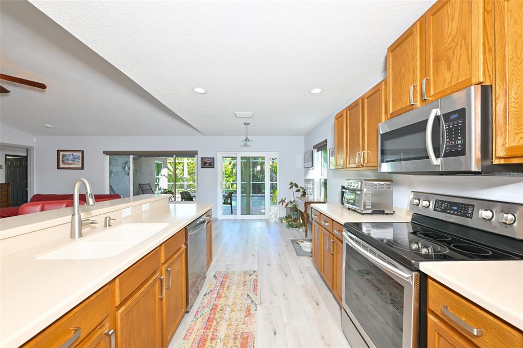 A kitchen with wood cabinets, stainless steel appliances, and a view of a backyard pool — 4061 KINGSFIELD DRIVE, PARRISH, FL