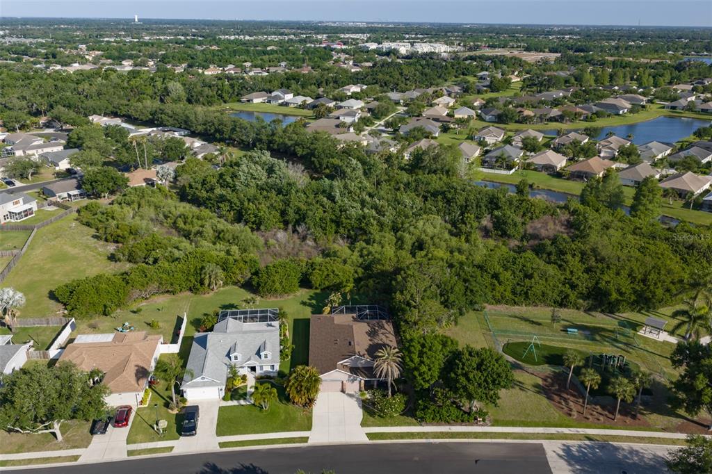 An aerial view shows two suburban houses with screened-in pools bordering a large wooded area — 4061 KINGSFIELD DRIVE, PARRISH, FL