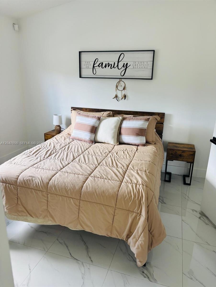 A bedroom features a bed with tan bedding, a wooden headboard, and a wall-mounted family sign — 8715 SW 152nd Ave # 312, Miami FL 33193, MIAMI, FL