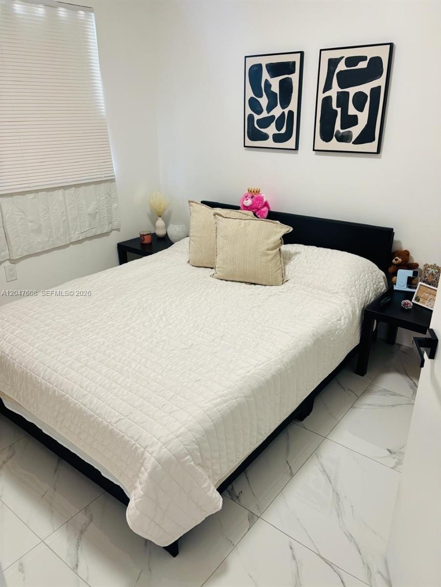 A bedroom features a black bed frame, white bedding, and two framed abstract art pieces — 8715 SW 152nd Ave # 312, Miami FL 33193, MIAMI, FL