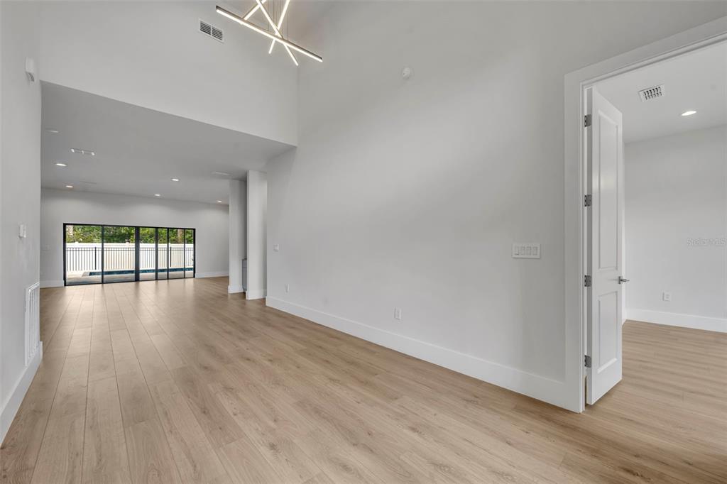 A bright, empty room features light wood-look flooring, white walls, and a modern light fixture — 102 BELL PLACE, WINTER PARK, FL