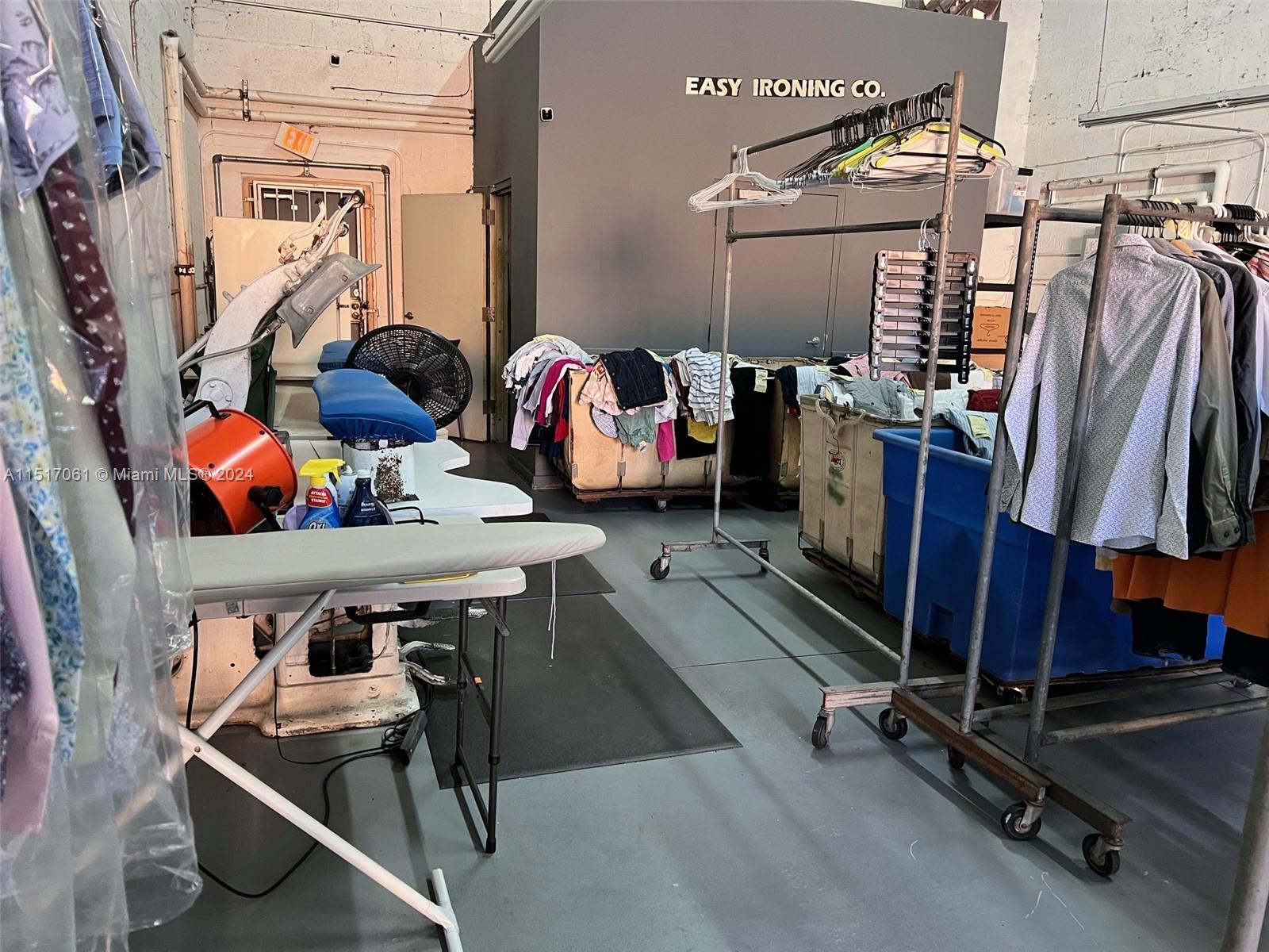 A commercial laundry room features ironing equipment, rolling garment racks, and bins of clothing — 8055 W 23rd Ave #2, Hialeah FL 33016, HIALEAH, FL