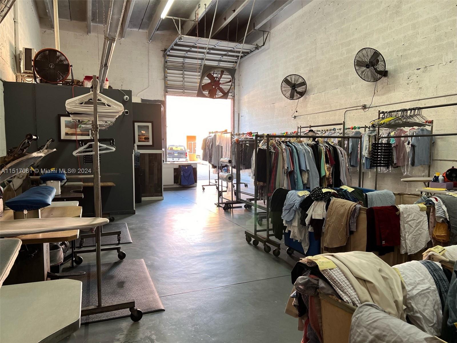 An industrial laundry or garment processing facility features clothing racks, ironing stations, and wall-mounted fans — 8055 W 23rd Ave #2, Hialeah FL 33016, HIALEAH, FL