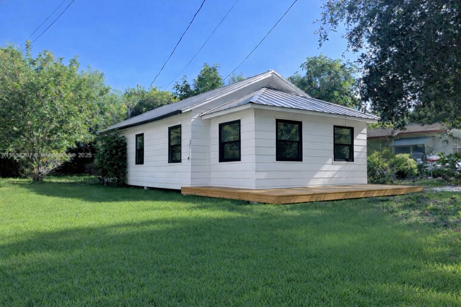 A white house with a metal roof and black-framed windows sits on a grassy lot — 156 Pearl Street, Boca Raton FL 33432, BOCA RATON, FL
