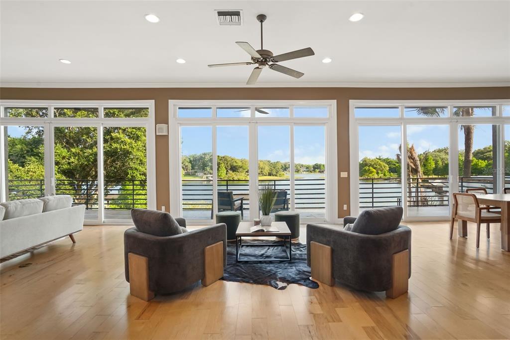 A living room features two armchairs, a coffee table, and large windows overlooking a lake — 1166 N LAKE SYBELIA, MAITLAND, FL