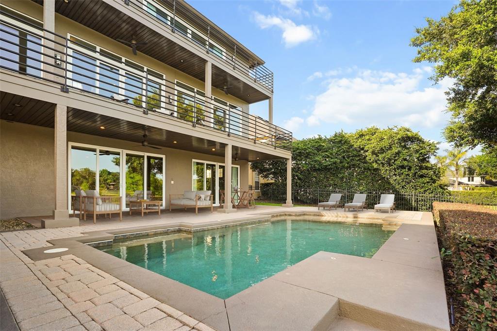 A two-story house with a balcony overlooks a backyard swimming pool and patio area — 1166 N LAKE SYBELIA, MAITLAND, FL