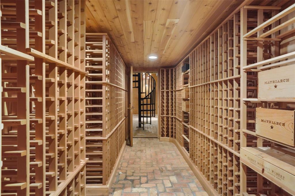 A wine cellar features wooden storage racks, a brick floor, and a spiral staircase beyond — 1166 N LAKE SYBELIA, MAITLAND, FL