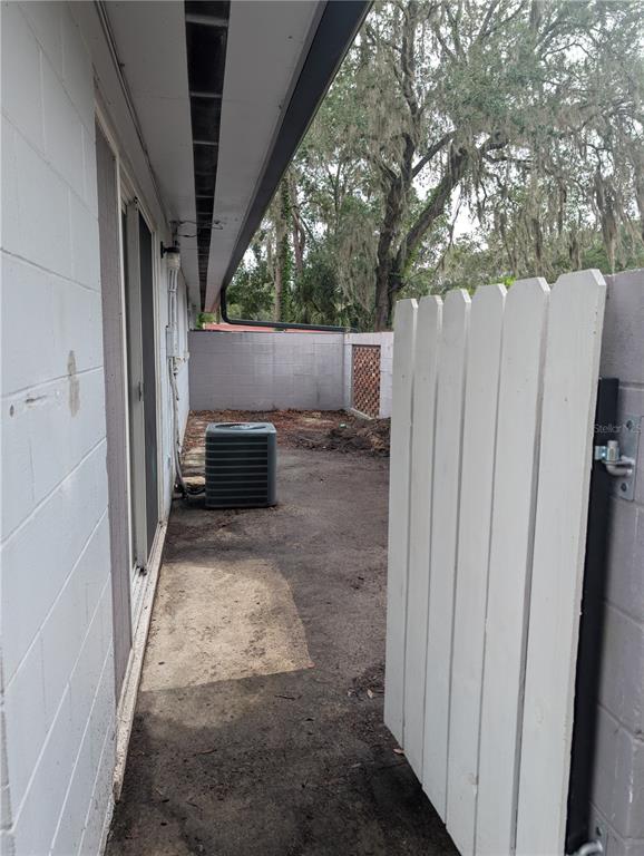 A side yard features a concrete patio, an air conditioning unit, and a white wooden gate — 803 NW 40TH AVENUE, GAINESVILLE, FL