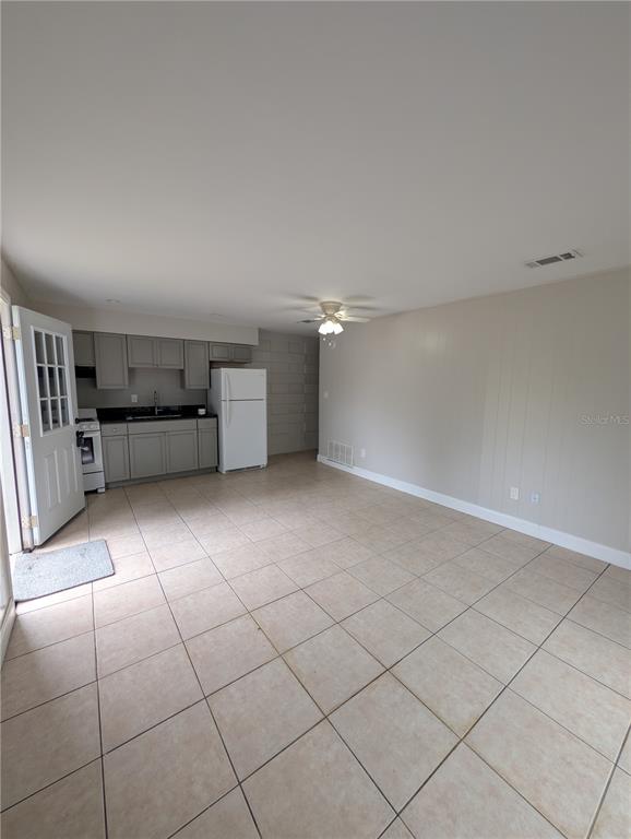 A room with light-colored tile flooring, a small kitchen area, and a white ceiling fan — 803 NW 40TH AVENUE, GAINESVILLE, FL