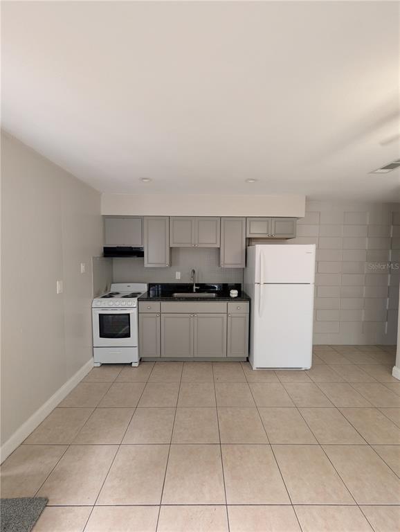 A kitchen features grey cabinets, a white stove, a white refrigerator, and tiled flooring — 803 NW 40TH AVENUE, GAINESVILLE, FL