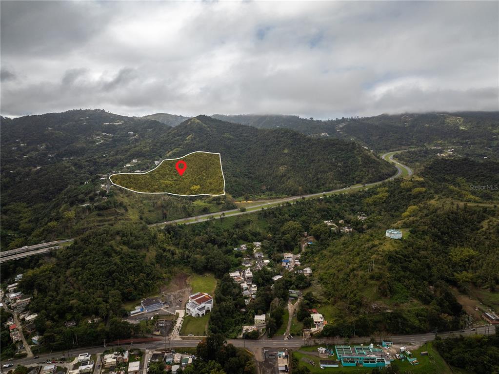 An aerial view shows a highlighted plot of land on a hillside near a highway — KM.HM 59 3 CARR 1, BO QUEBRADA ARRIBA, CAYEY, PR