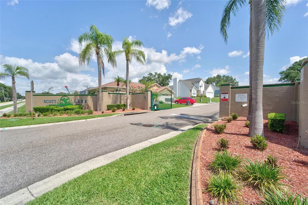 The entrance to the Scott Lake community features a gated road, palm trees, and signage — 692 JESSANDA CIRCLE, LAKELAND, FL