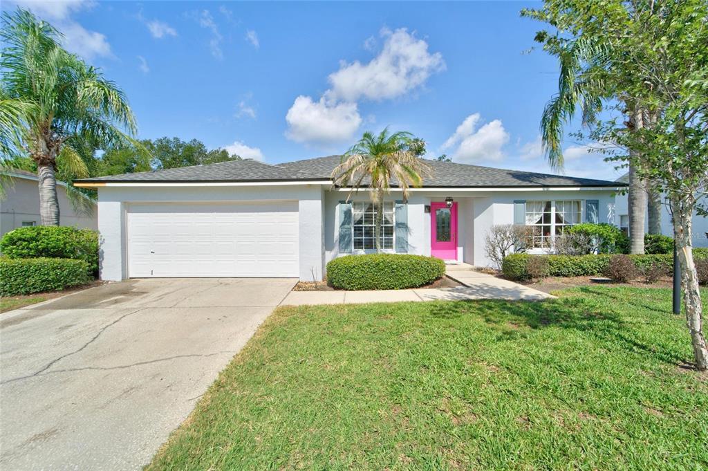 A single-story house with a white exterior, a two-car garage, and a bright pink door — 692 JESSANDA CIRCLE, LAKELAND, FL