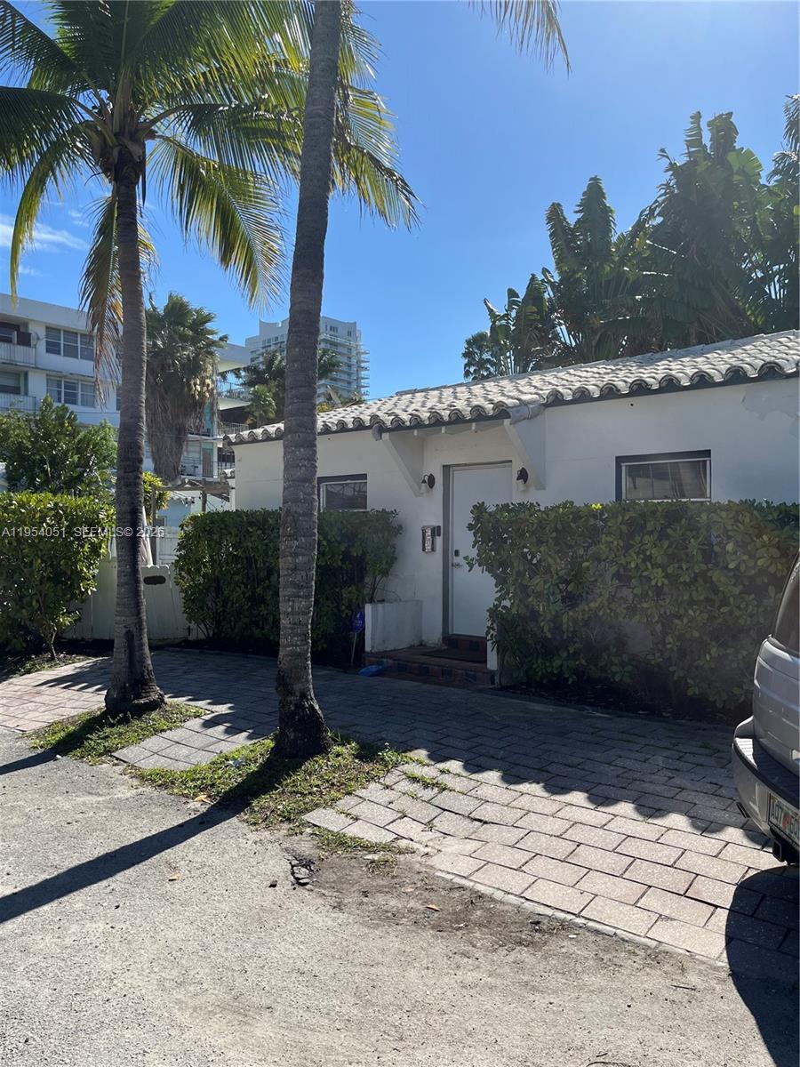 A white one-story house with a tiled roof stands behind a paved driveway and palms — 6 Farrey Ln, Miami Beach FL 33139, MIAMI BEACH, FL