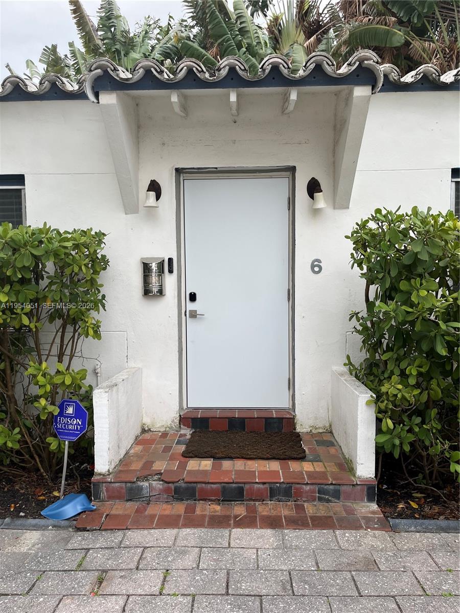 The exterior of a white building features a front door marked with the number six — 6 Farrey Ln, Miami Beach FL 33139, MIAMI BEACH, FL