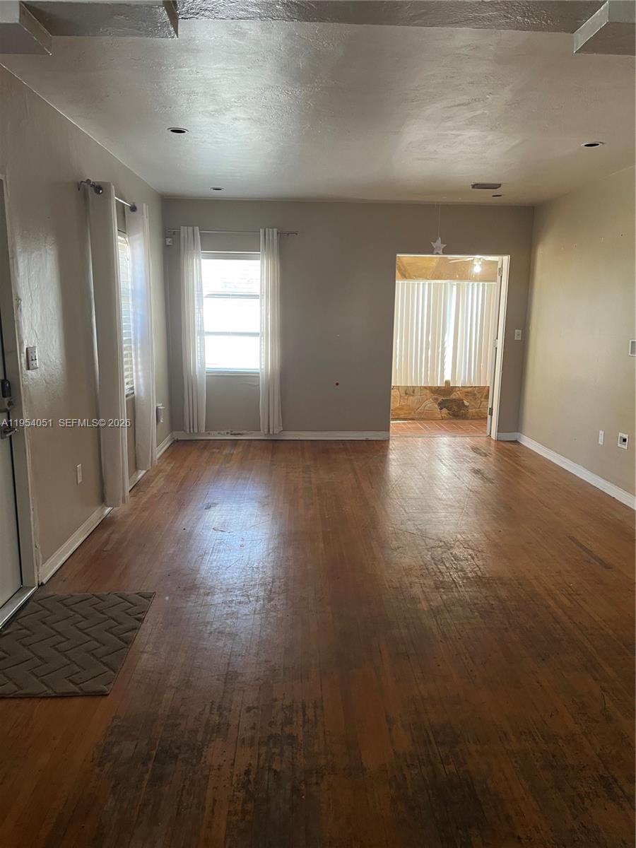 A living room features hardwood floors, light-colored walls, and a doorway leading to a sunroom — 6 Farrey Ln, Miami Beach FL 33139, MIAMI BEACH, FL