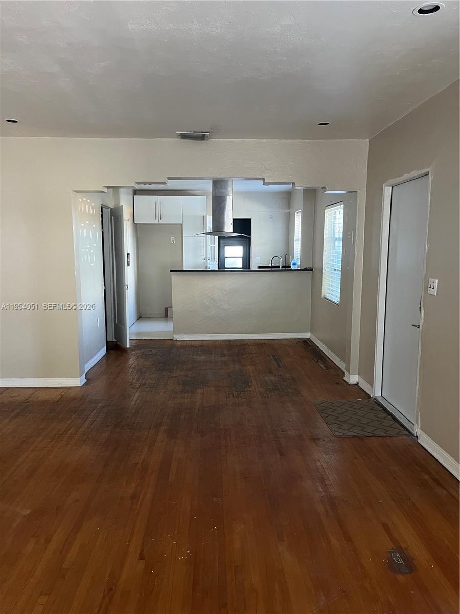 A living area with hardwood floors leads to an open kitchen with a breakfast bar — 6 Farrey Ln, Miami Beach FL 33139, MIAMI BEACH, FL