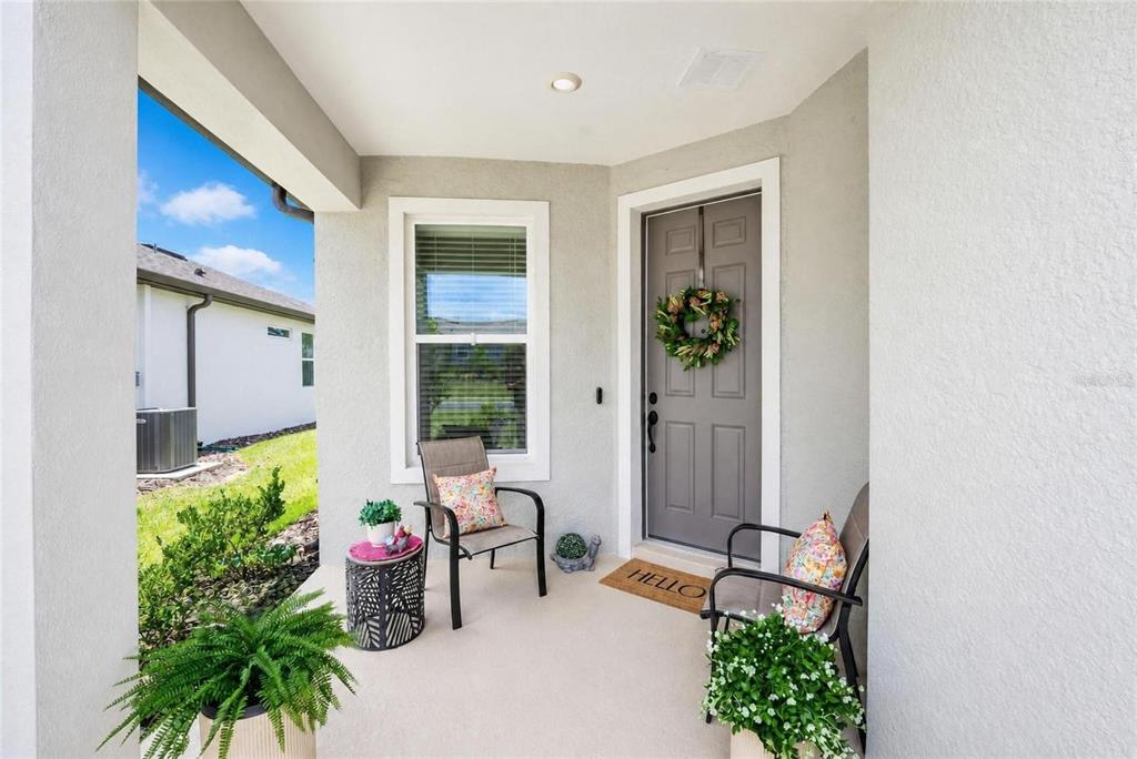 A covered front porch features a gray door, two chairs, and potted plants — 8764 SW 58TH STREET ROAD, OCALA, FL