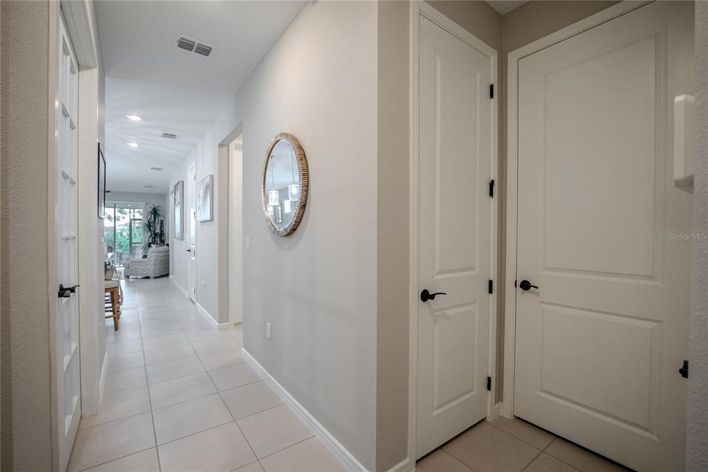 A hallway with light tile flooring, white walls, and several closed doors leads to a living area — 8764 SW 58TH STREET ROAD, OCALA, FL